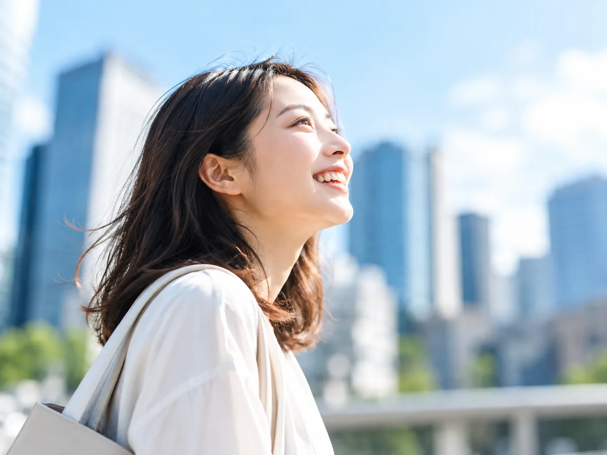 街を見上げて笑う女性(イメージ)